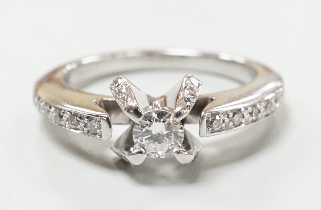 A modern 18ct white gold and claw set single stone diamond ring, with diamond chip set shoulders, size M, gross weight 5.2 grams.